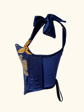 Load image into Gallery viewer, A side view of the Anna stays. There is a side fell seam and a side front fell seam. The tied back lacing is visible. The waistline scoops down from back to front.