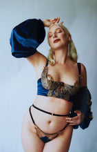 Load image into Gallery viewer, A woman viewed from the front wearing the Anna bra, thong and sleeves, she holds her hand over her head. The blue silk of the sleeve drapes down.