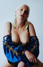 Load image into Gallery viewer, A woman wearing the Anna 1/4 cup bra and sleeves. The model has her hands crossed with the sleeves draping across her body. The sleeves are blue silk with gold lace inserts.