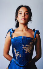 Load image into Gallery viewer, A front view of a woman in the Anna stays. The centre front has a split down to the the bust line. There are pearls and gold lace decorating the front