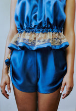 Load image into Gallery viewer, A front view of the silk tap pants the roses are visible on the sides. The hem of the tap pants drapes down towards to the centre.