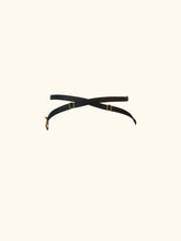 Load image into Gallery viewer, A side view of the Anna thong. The black straps cross over and pass around the waist. The sliders are gold.