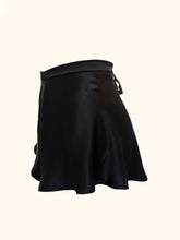 Load image into Gallery viewer, A side view of the Emmeline black silk tap pants. The silk satin gently catches the light as it flows over the hips. The waistband sits on the waist and the legs extend to the top of the thigh.