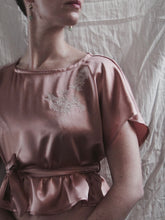Load image into Gallery viewer, A model wears the Sarah lounge top with the waist tie. The tie sits at a low empire line, the top flares out to the high hip.