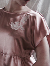 Load image into Gallery viewer, A model wears the Sarah lounge top without the waist tie. This is a close up of the shoulder and applique. The neckline is wide and shows the collar bones.