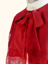Load image into Gallery viewer, A close up of the bow at the front of the cape-let. The bow is wider at the ends than at its start.