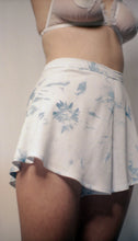 Load image into Gallery viewer, An image shot from below showing the side front of the indigo tap pants. The fabric falls in soft folds from the waist. The front is plain in style, leaving the pattern of the indigo dye to be the main feature. The model also wears the Lily bralette in off white cotton tulle.