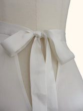 Load image into Gallery viewer, Close up of the bow fastening of the ivory sandwashed Emmeline tap pants on a stand. Showing the matte nature of the silk and the v shaped gap beneath the bow.