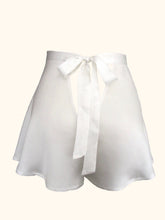 Load image into Gallery viewer, A back view of the ivory sandwashed silk Emmeline tap pants. Showing the triangular cut out beneath the bow fastening and the length of the bow, which extends almost to the bottom of the legs of the pants.