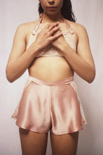 Load image into Gallery viewer, A model shown from the front wearing the Sarah tap pants. The front of the tap pants is bias cut pink silk. You can see the lace panels at the side. The pants end a few inches past the top of thigh.
