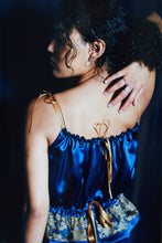 Load image into Gallery viewer, back view of a woman wearing a gathered blue silk camisole it ties with gold ribbons at the neck and waist
