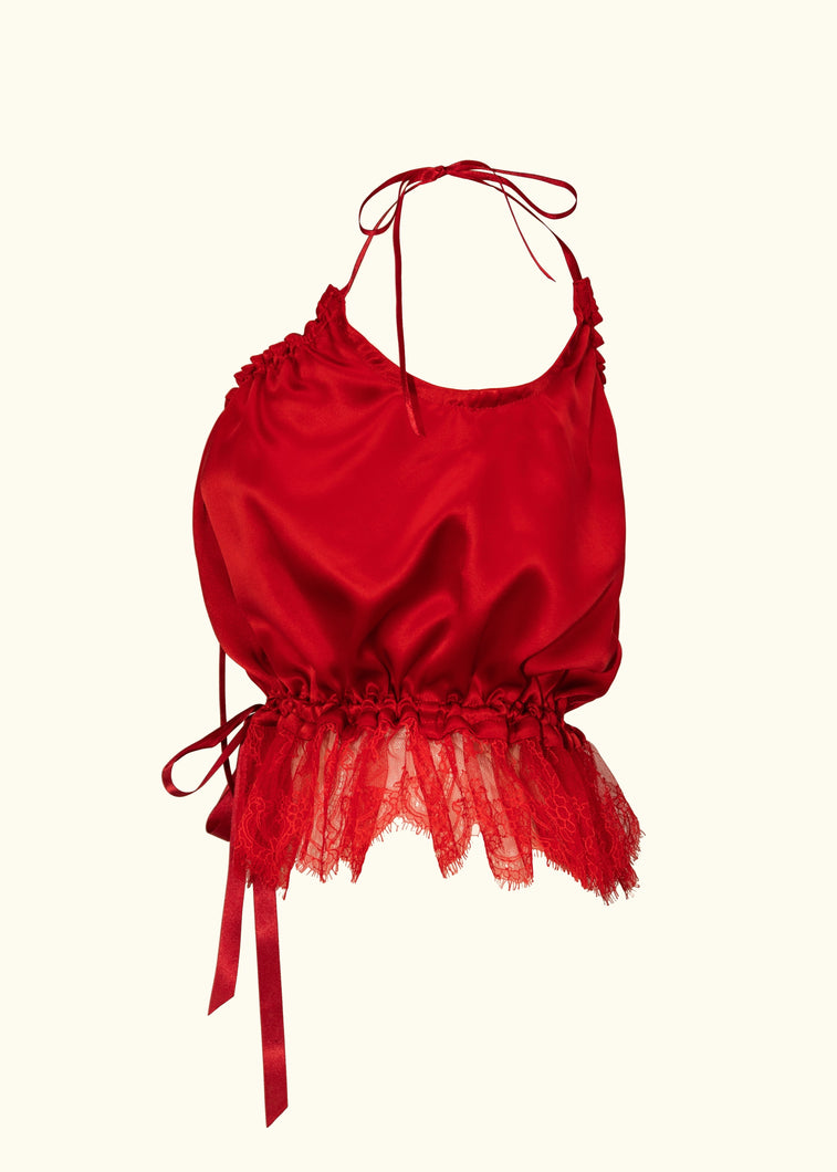 A side view of the red silk cami. The hem is trimmed with deep lace that starts at the waist and flares over the hips. the waist is gathered in on a red ribbon. The front and back necklines both scoop down an equal amount.