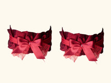 Charger l&#39;image dans la galerie, Front view of a pair of dark red garters. They are decorated iwth red bows with tiny glass beads in the centre.
