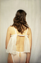 Charger l&#39;image dans la galerie, A woman wears the Lily cami and knickers. The back has a gap joined by an adjustable strap. The strap is covered in silk. The back of the cami is sits lower than the front and reaches the high hip.
