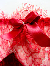 Cargar imagen en el visor de la galería, A close up of the deep red bow on the hipline of the knickers. It has two small, clear glass beads sewn into the centre and is layered with red lace. The ribbon has a satin finish.
