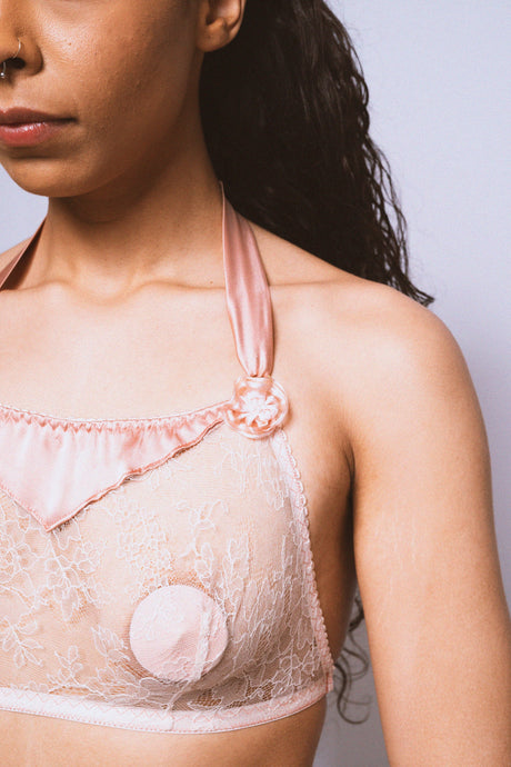 A close up of one side of the sheer Sarah bralette. The lace is delicate and floral. The silk halter strap is around 1 inch wide. There is a shallow triangular silk panel extending down from the neckline at the centre front.