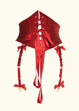 Cargar imagen en el visor de la galería, The red silk douppion corset belt from the back. The lacing is red ribbon and there are 2 visible suspenders hanging down from the bottom. The clips are gold and are trimmed at the top and bottom of the straps with red ribbon bows.
