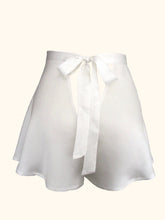 Cargar imagen en el visor de la galería, A back view of the ivory sandwashed silk Emmeline tap pants. Showing the triangular cut out beneath the bow fastening and the length of the bow, which extends almost to the bottom of the legs of the pants.
