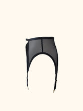 Cargar imagen en el visor de la galería, The side of the Win suspender belt. The side and back are made in sheer black mesh. There is a narrow side seam. The straps sweep up in a high arc at the sides. There is a 1.5cm wide black waistband.
